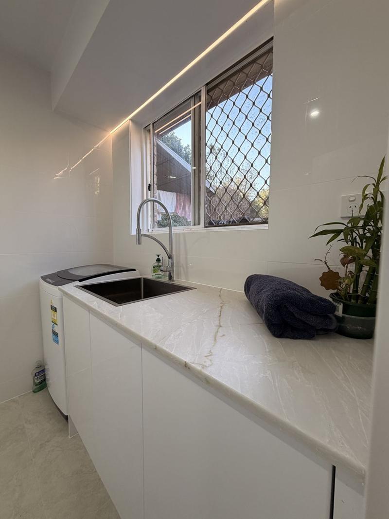 Stone laundry benchtop with an undermount sink, pull-down tap and LED strip lighting